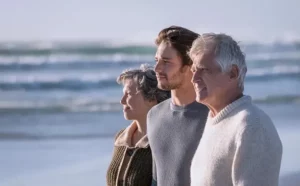 Trois membres d'une famille de trois générations regardant vers la mer.