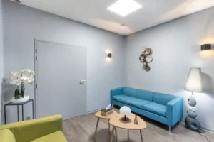 Salon de recueillement chaleureux avec canapé bleu et fauteuil pour les familles.